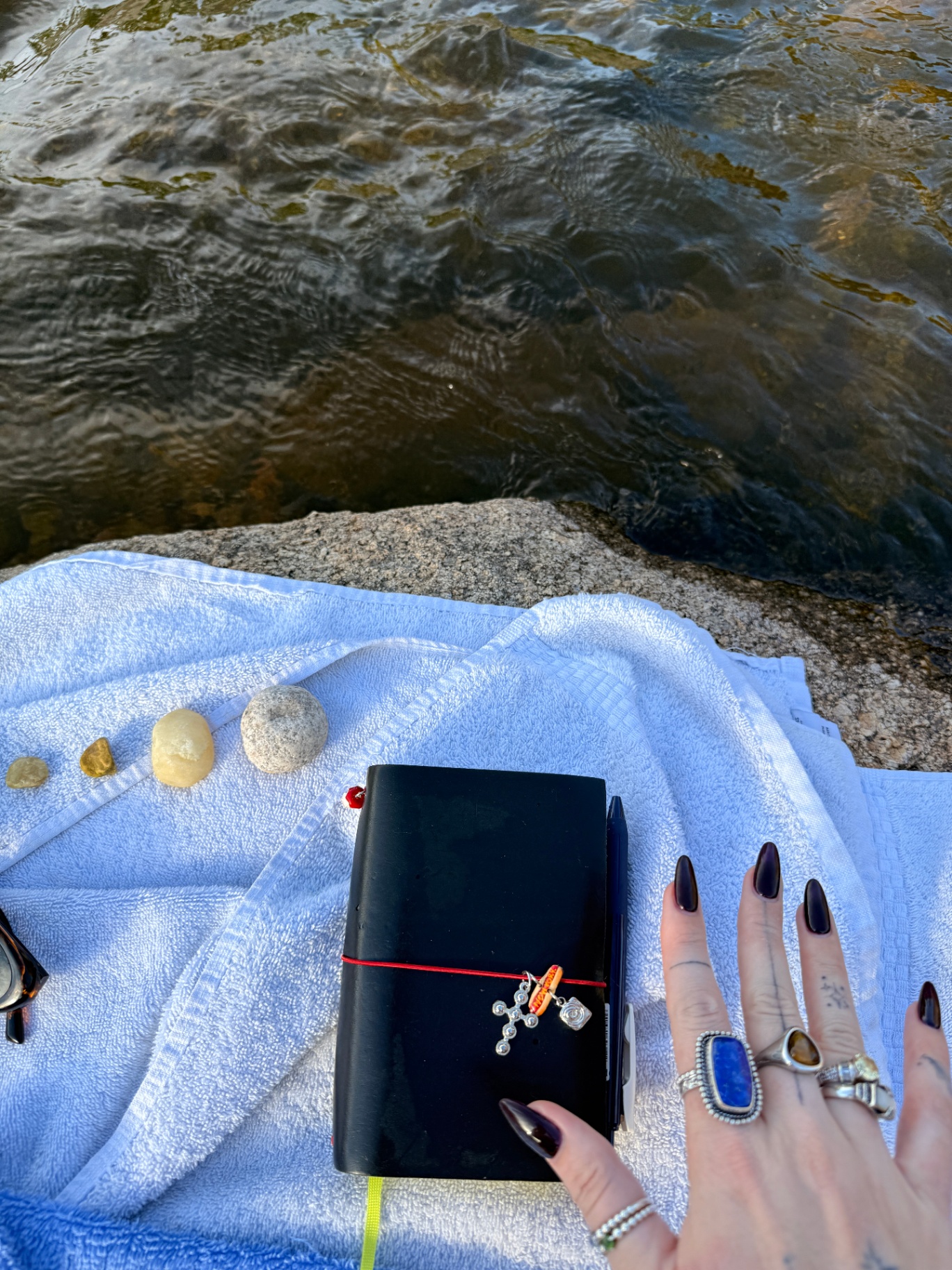pocket journal by the water with rocks and rings